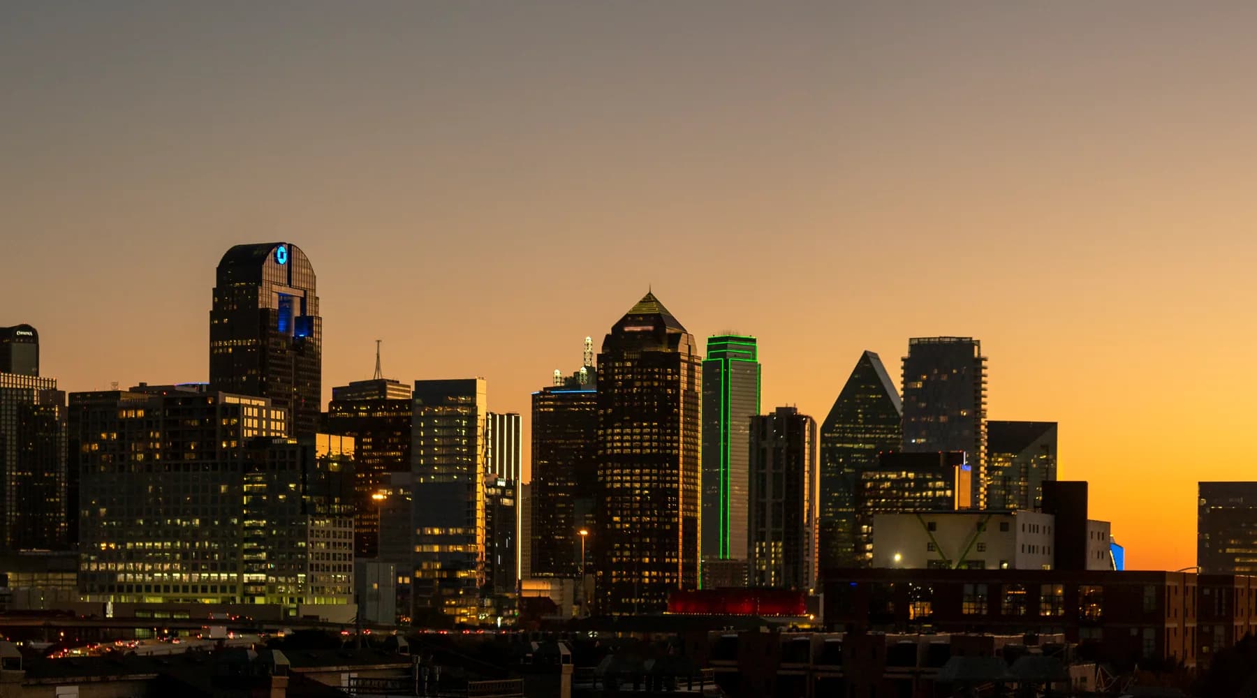 Dallas skyline at dusk beneath an orange sky