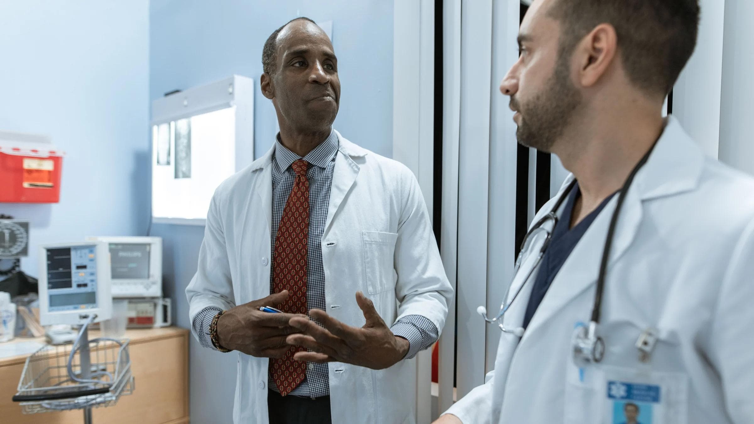 Two doctors in lab coats discussing an X-ray in a clinical setting.