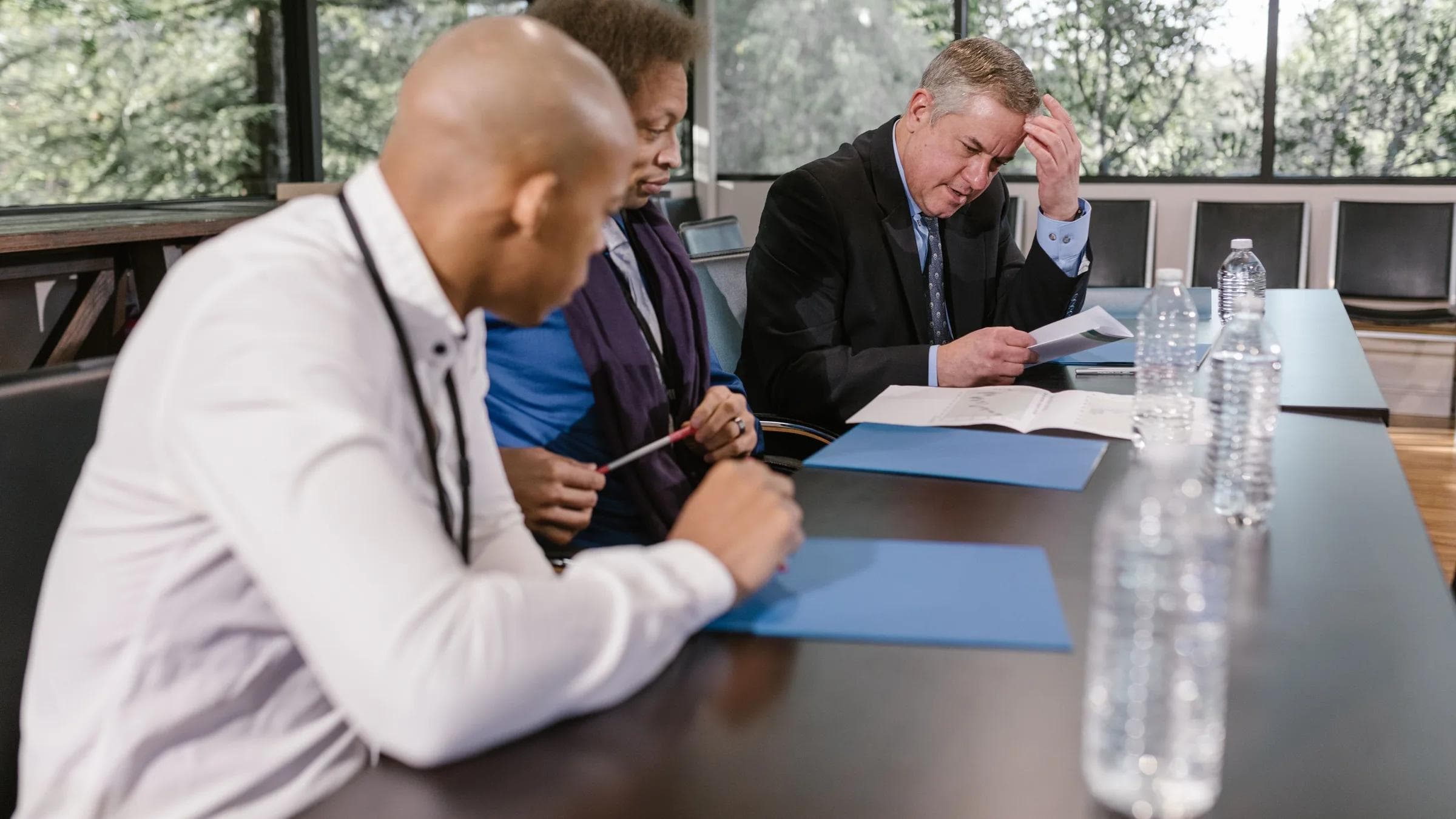 Group of diverse colleagues in a business meeting reviewing documents indoors.