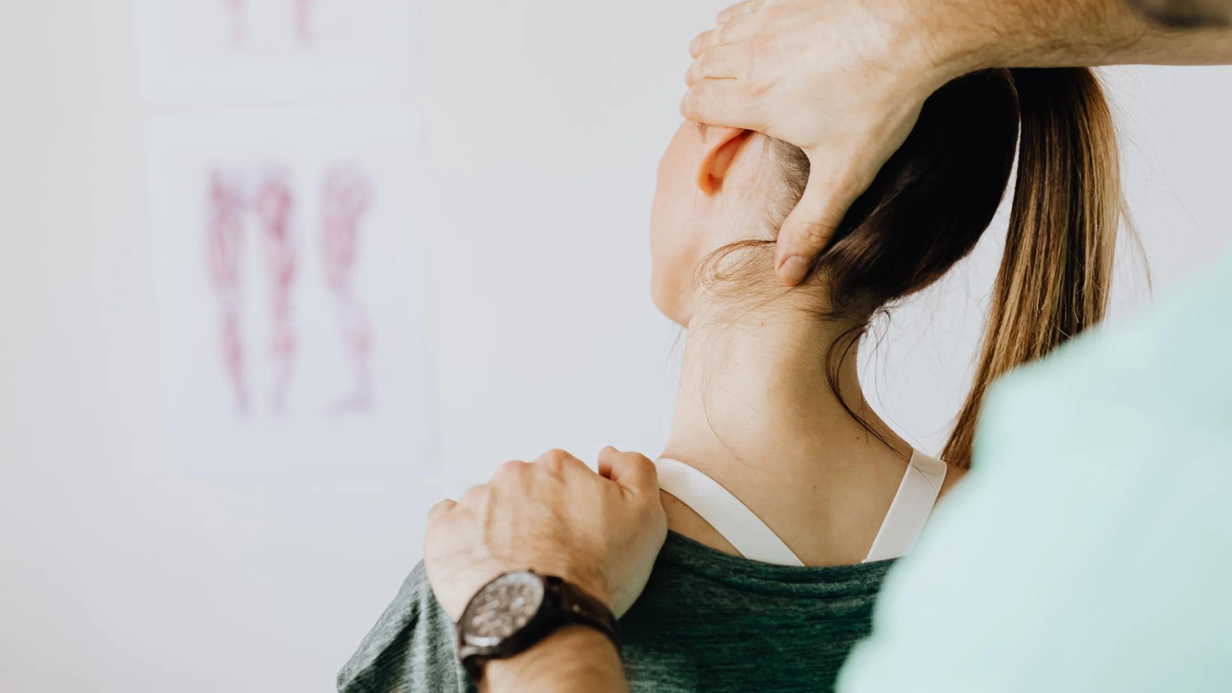 A clinician assesses an adult patient's neck movement in an office.
