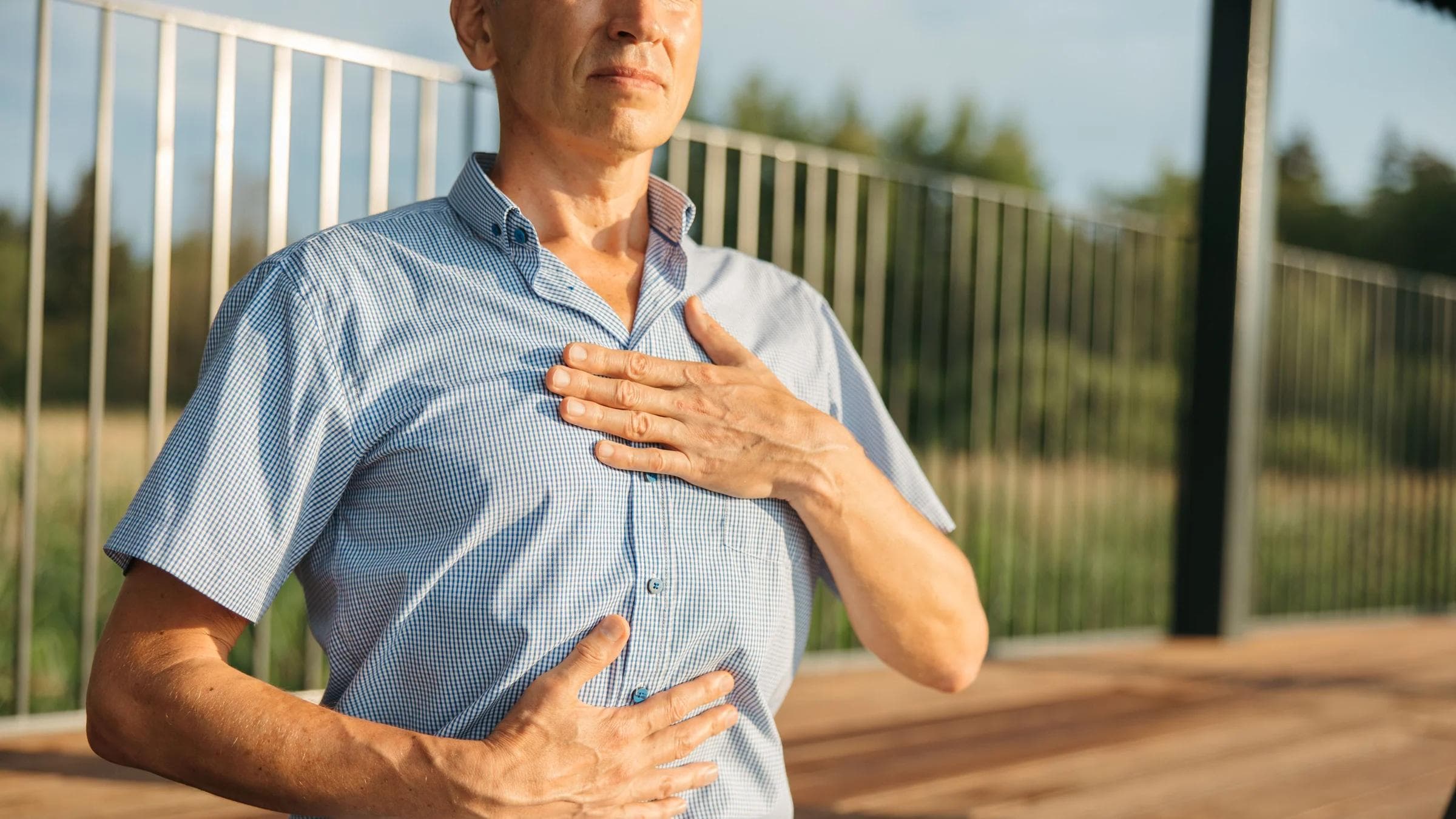A man practicing relaxation with hands on chest and abdomen outdoors.