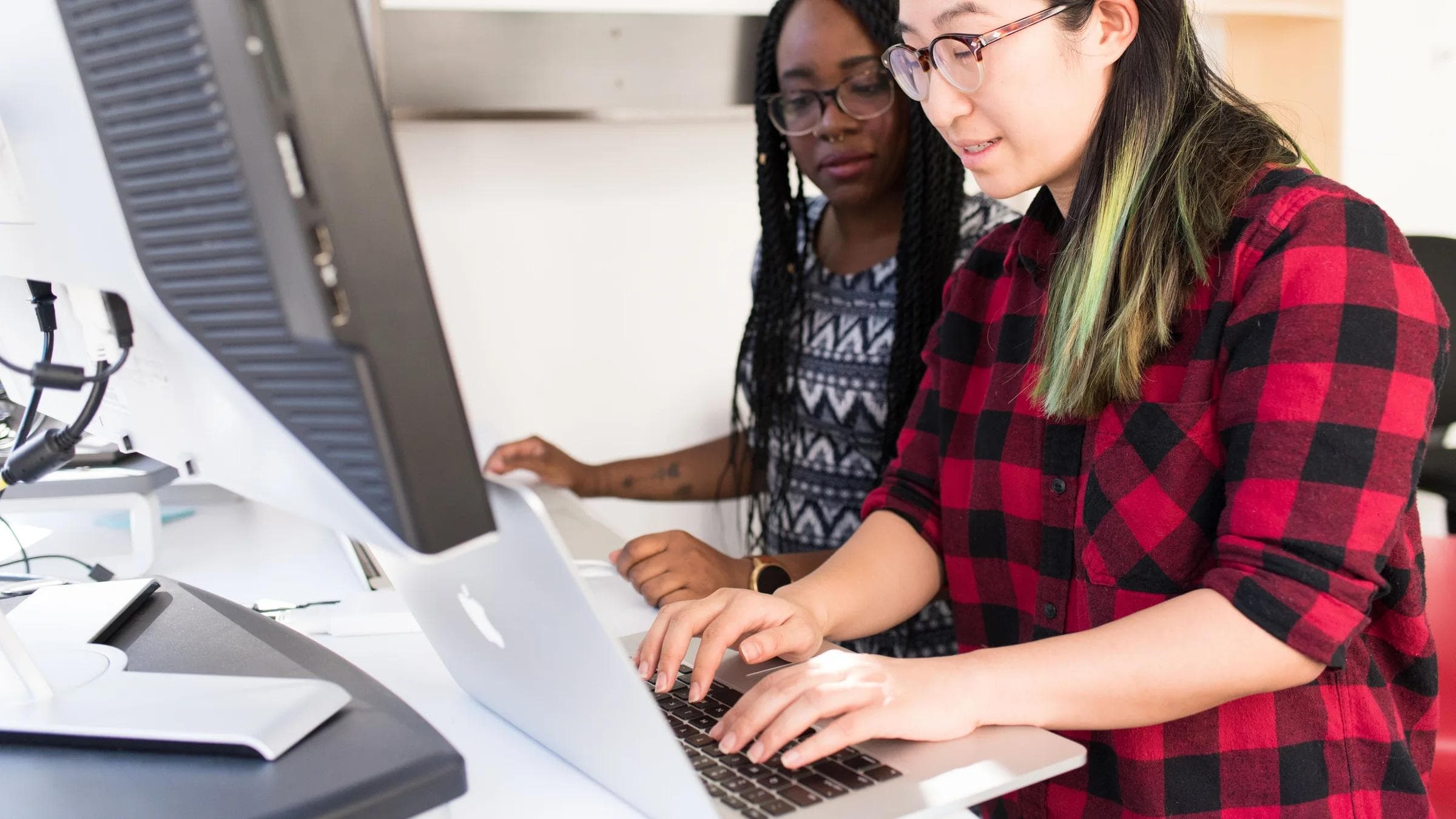 Two female developers collaborating on a project in a modern office setting.
