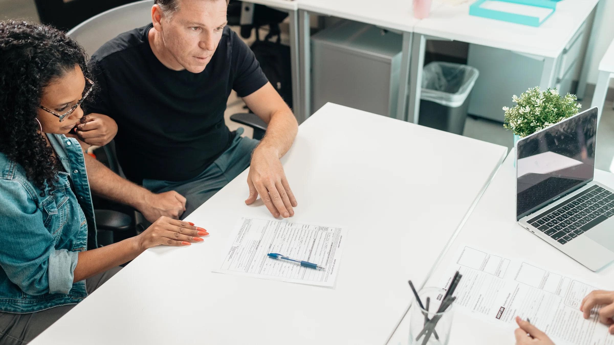 A couple discusses legal documents with a professional in a modern office setting.