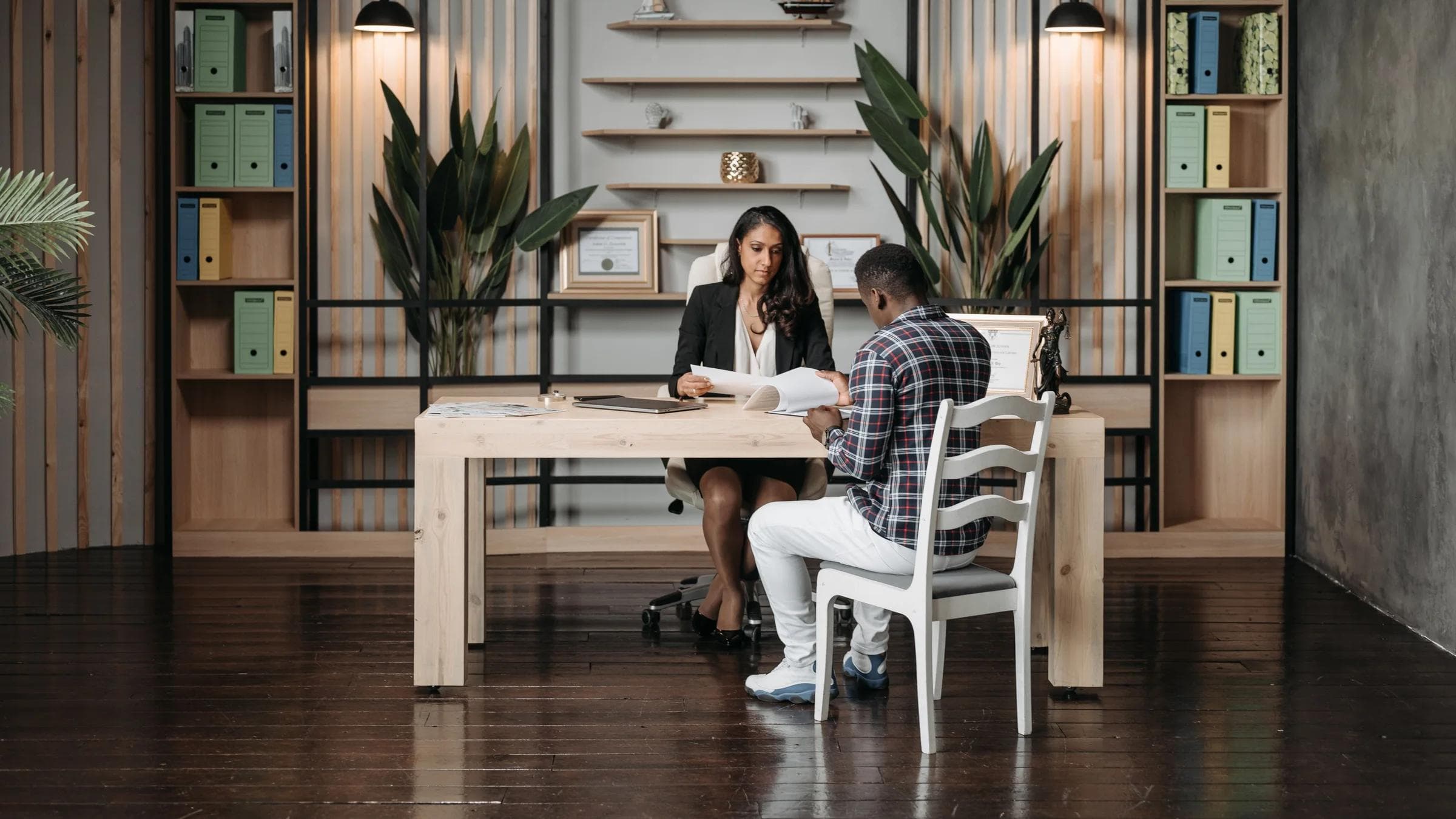 A lawyer consulting a client in a modern office with organized paperwork and decor.