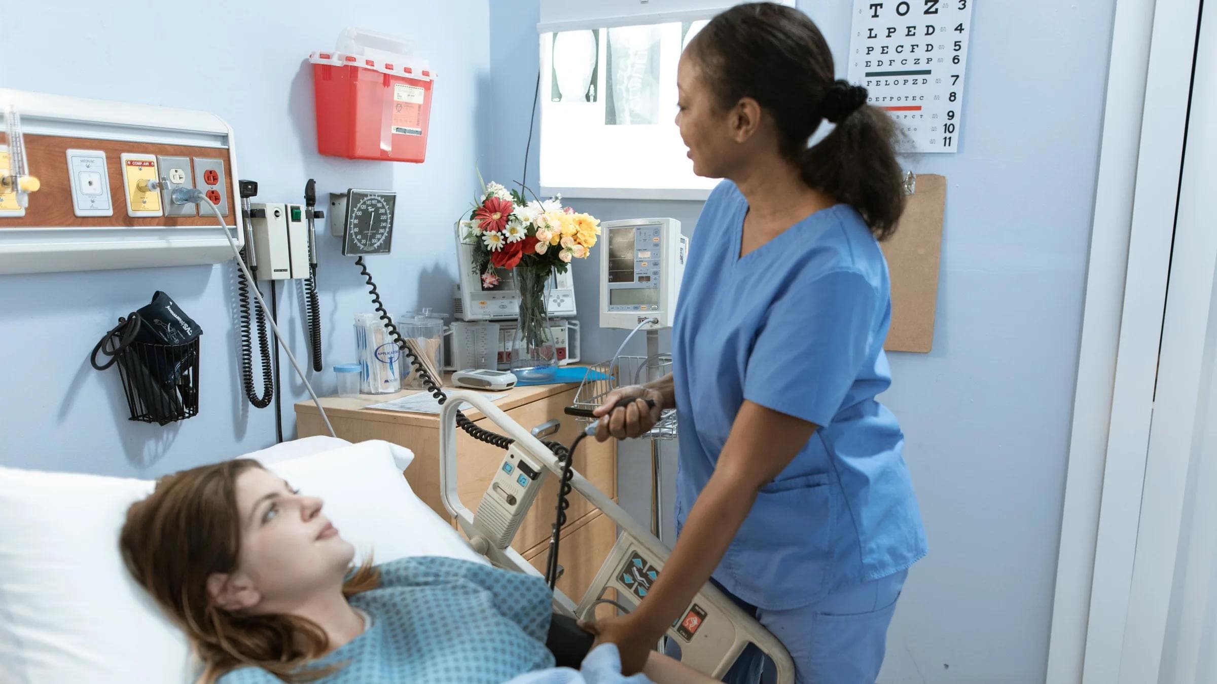 Nurse providing care to a patient in a hospital room with medical equipment.