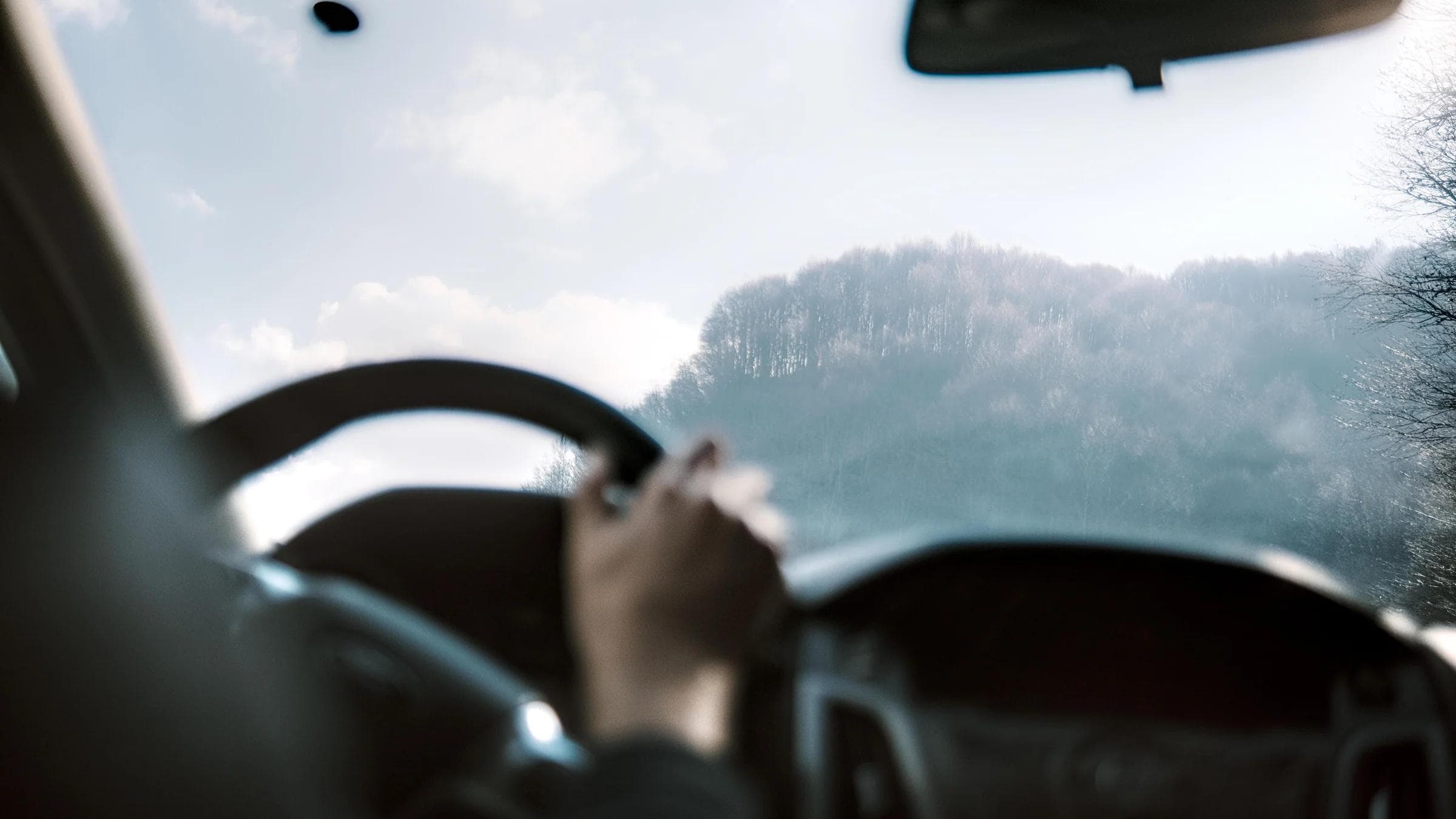 View from inside a car driving through a winter mountain landscape, capturing a serene road trip experience.
