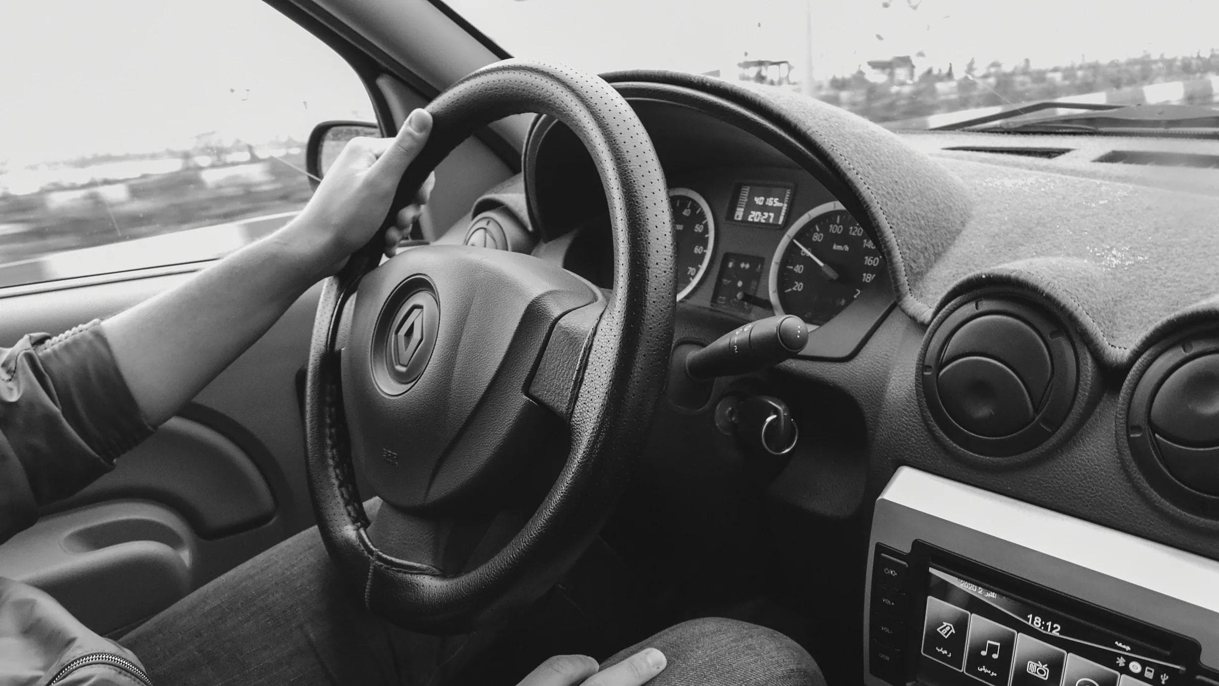 Crop unrecognizable male driver sitting in automobile cabin with steering wheel and computer.