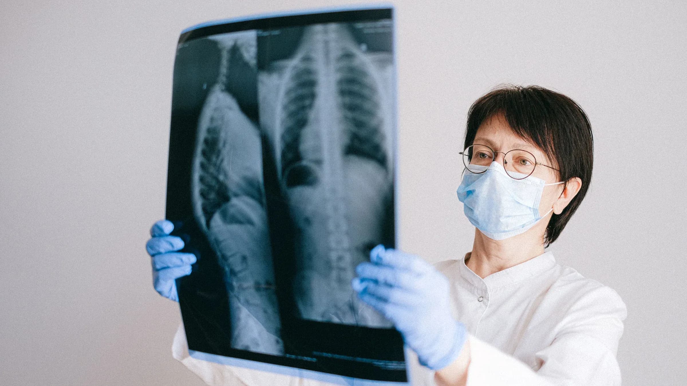 Doctor in protective gear examining chest x-ray for diagnosis.