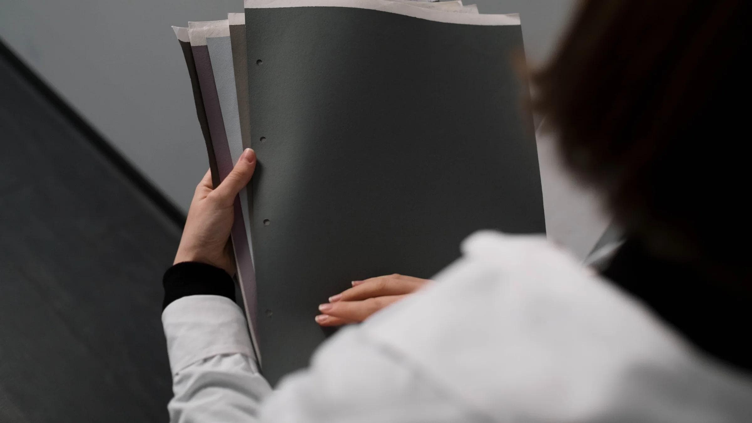 Close-up of a businesswoman holding and reviewing documents in an office setting.