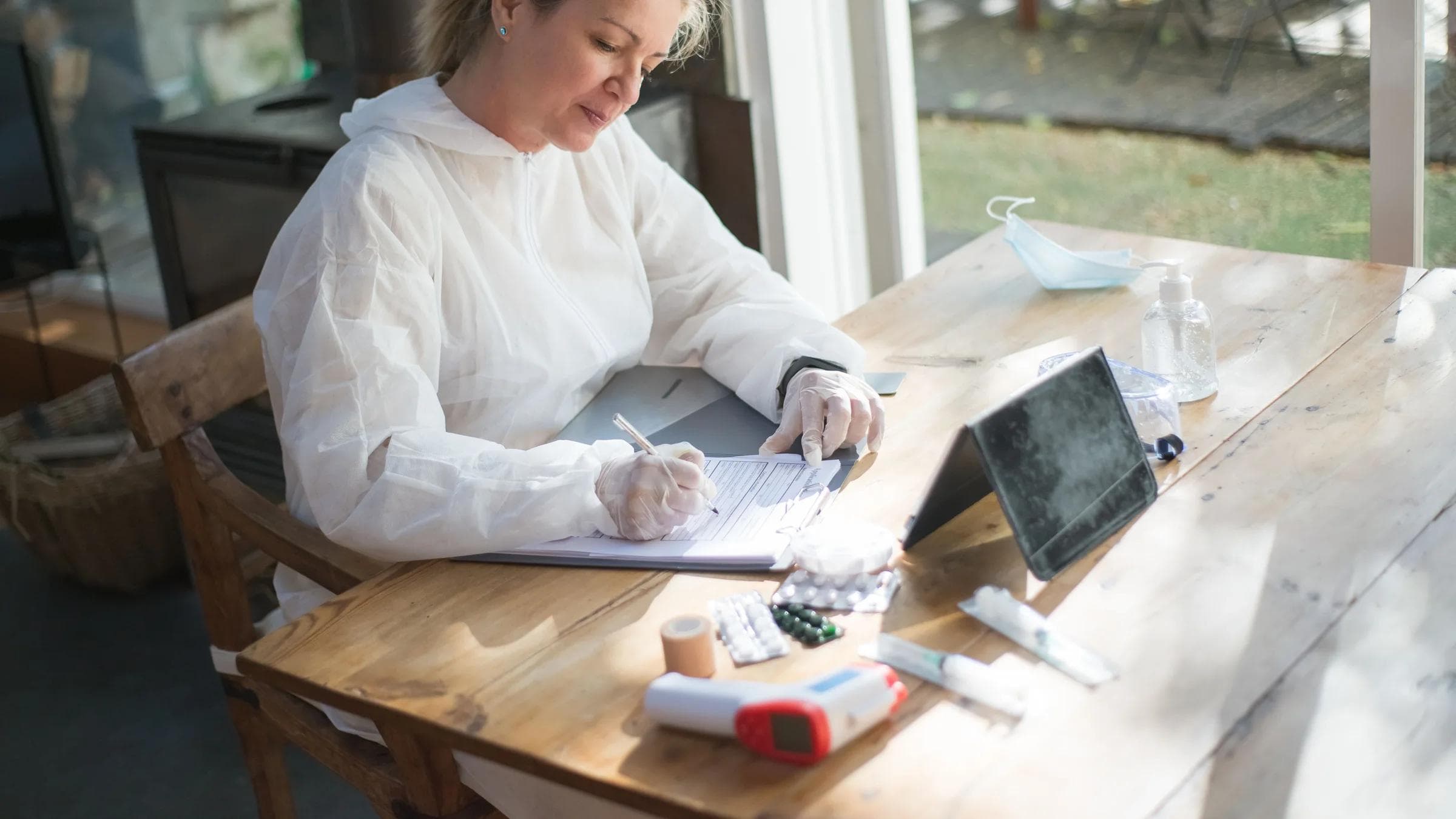 A healthcare professional writes patient notes on a clipboard.