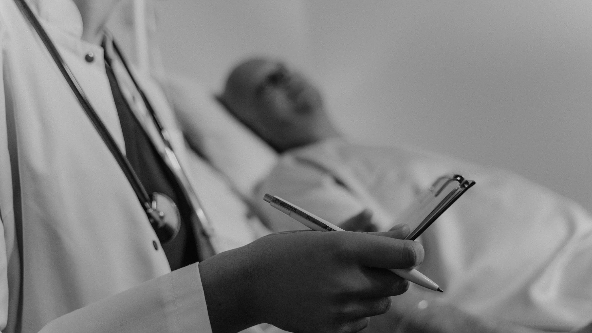 A clinician takes notes while speaking with a patient during an appointment.