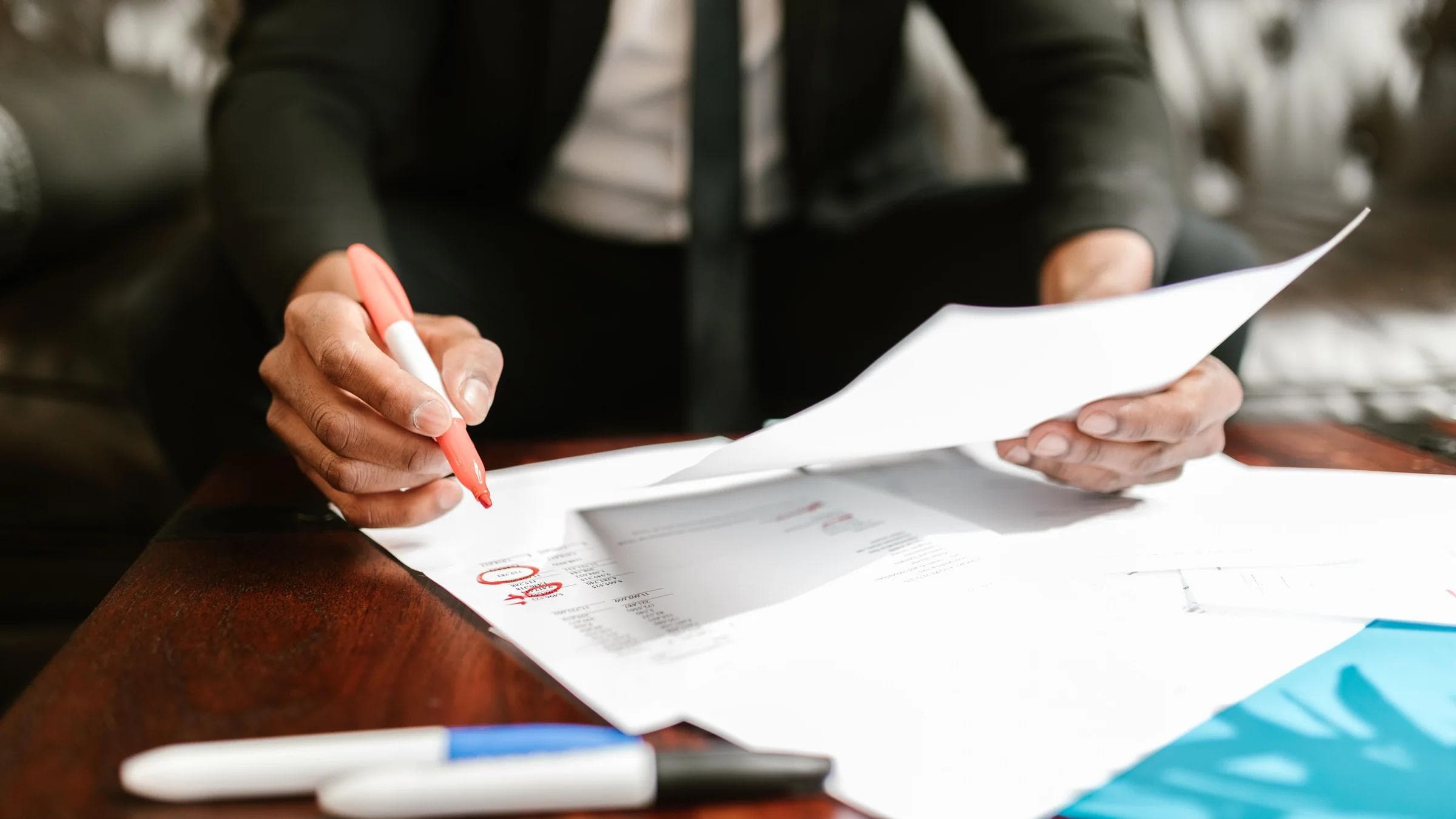 Businessman working with financial documents at office desk, highlighting details.