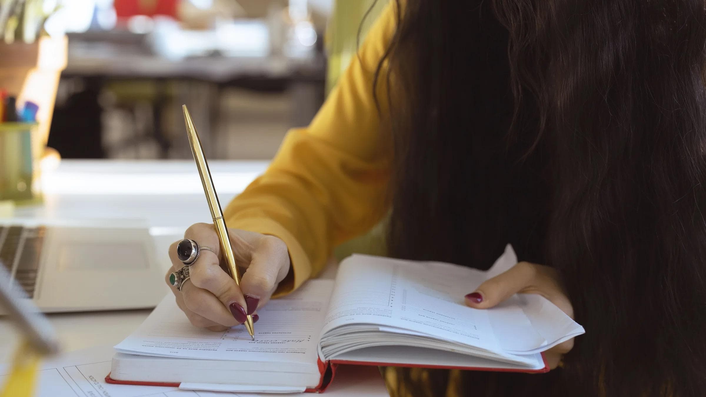 Close-up of a woman writing in a notebook, focusing on hand and pen, suitable for productivity themes.