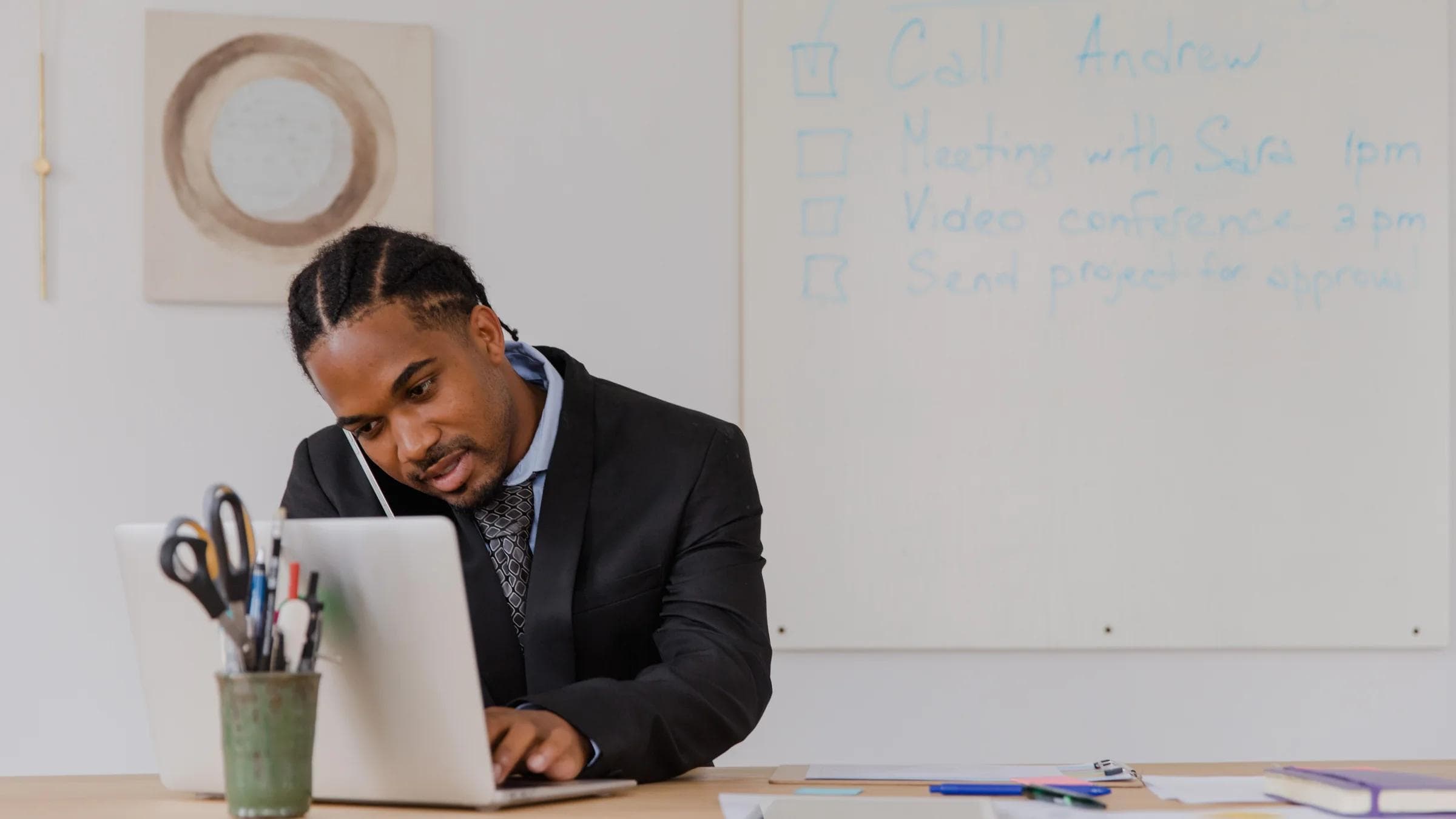 Businessman at his desk in an office working on a laptop and making phone calls.