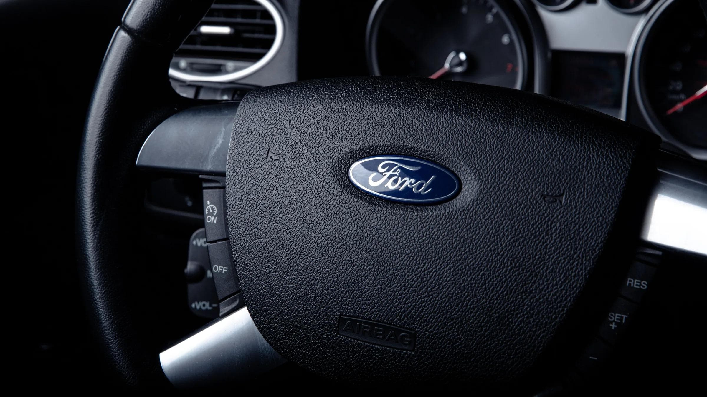 Detailed close-up of a Ford car steering wheel with instrument panel visible in the background.