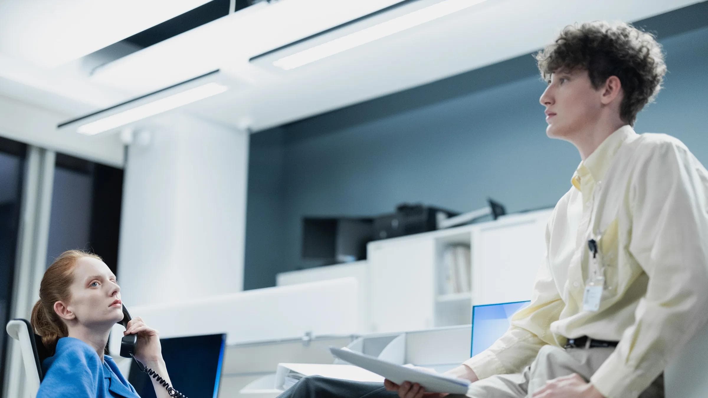 Two office workers engage in conversation, creating a professional work ambiance.