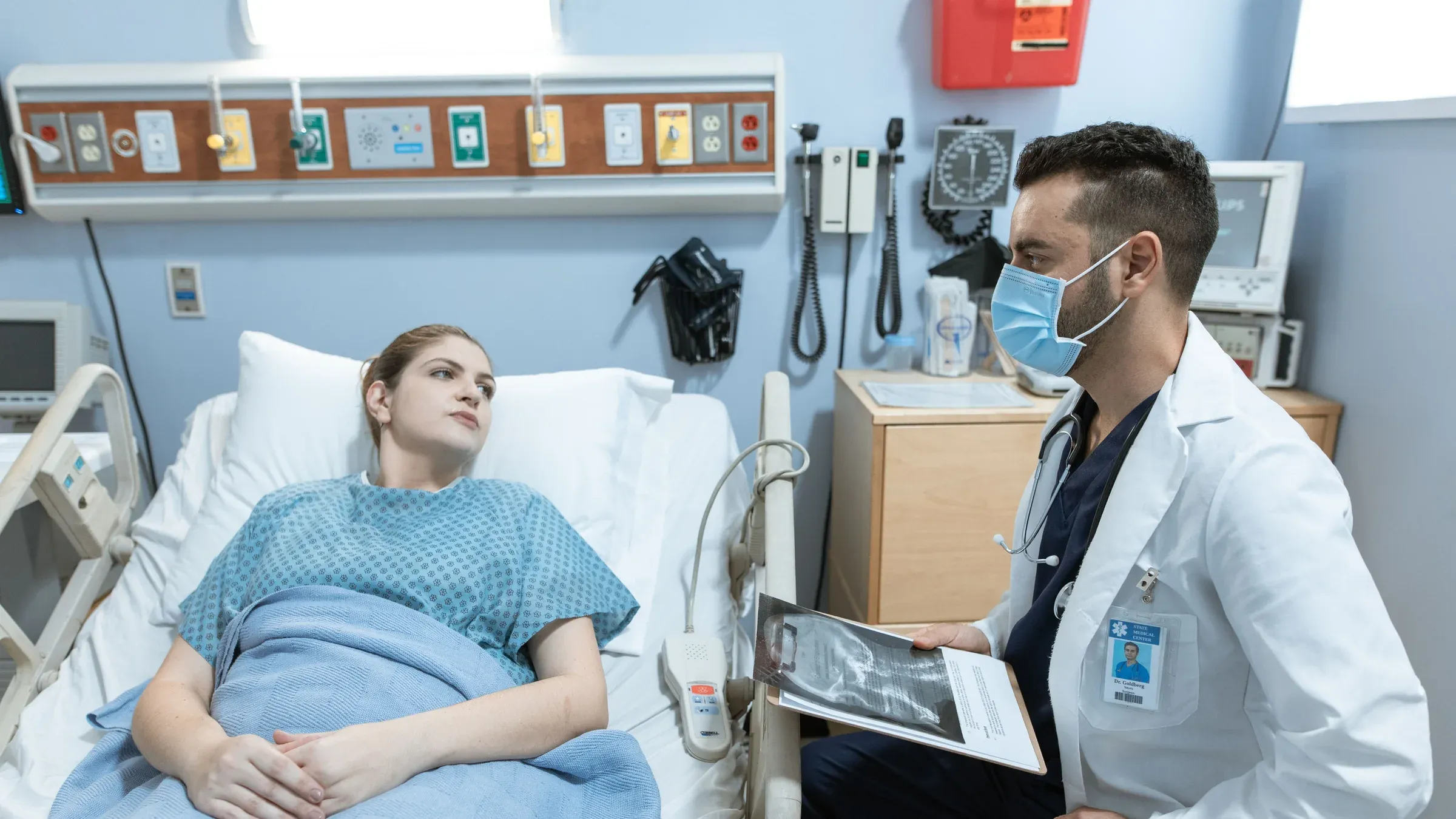 A medical practitioner discusses health details with a patient in a hospital setting.