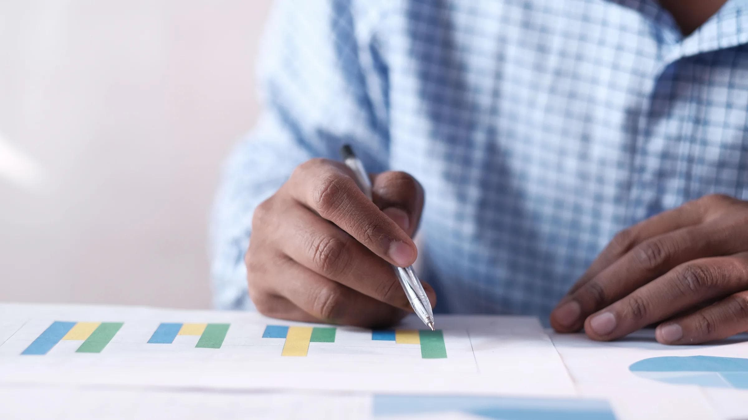 Close-up of hands analyzing colorful graphs, indicating business planning.