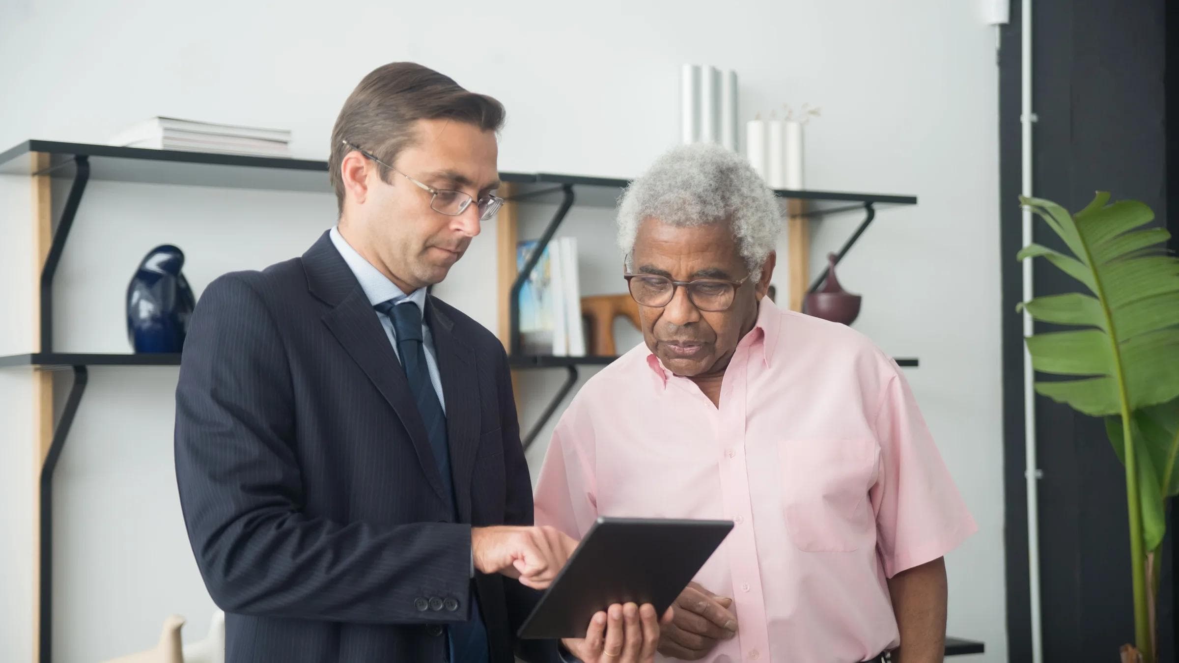 Two men discussing business strategies using a digital tablet in an office.