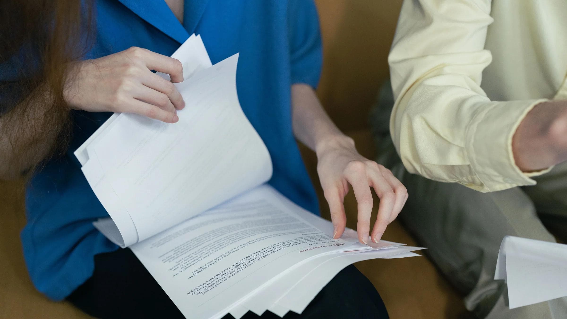People in professional attire reviewing important documents together on a sofa.