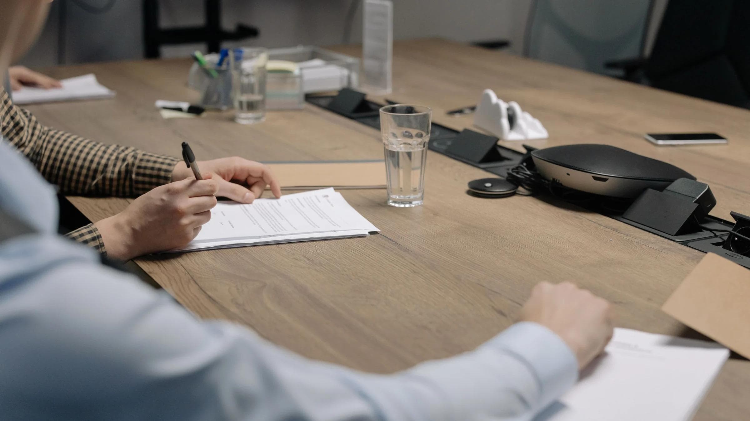 Professional setting of a business meeting with individuals signing documents on a conference table.