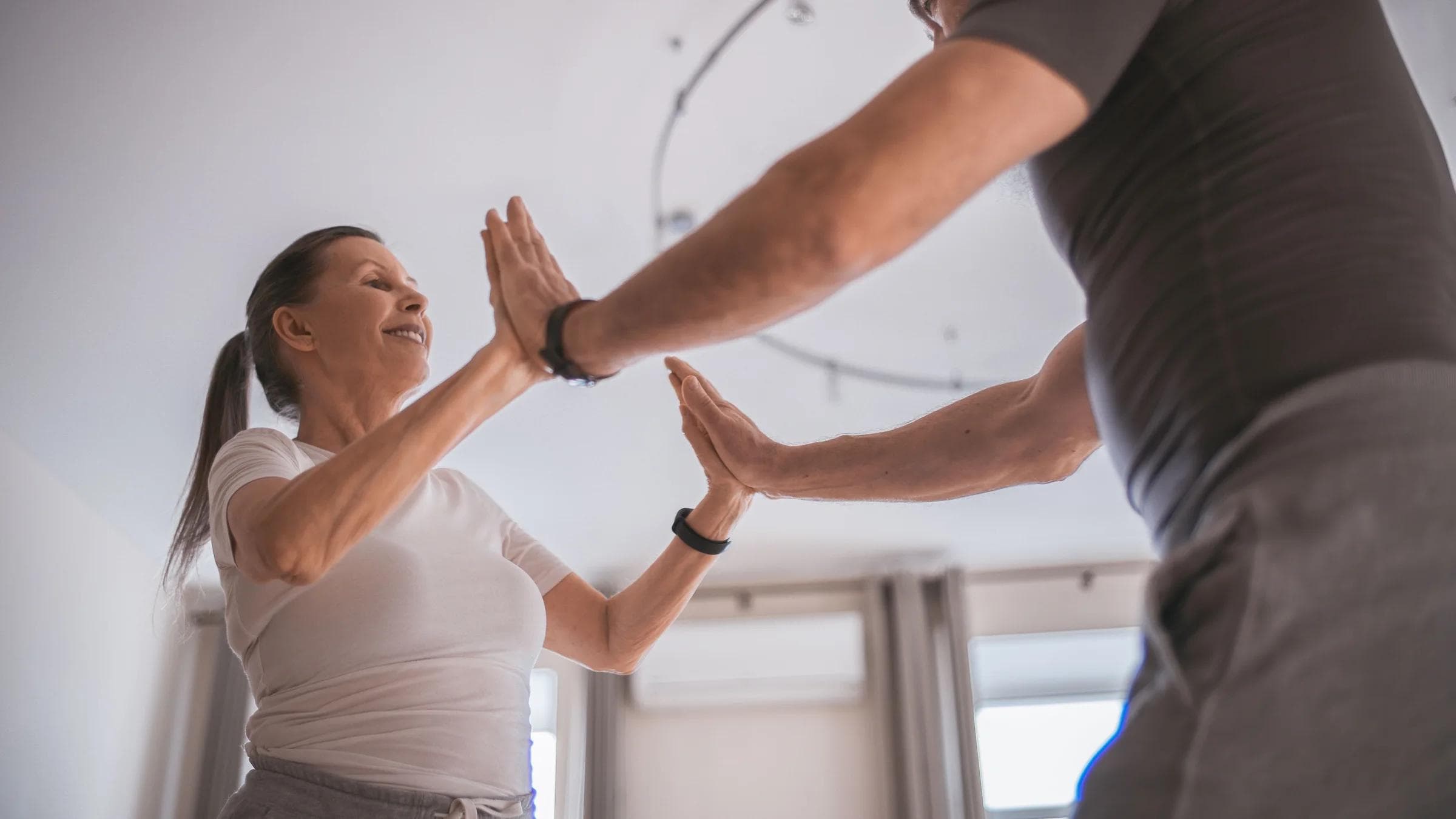 A senior couple joyfully exercising indoors, emphasizing health and togetherness.