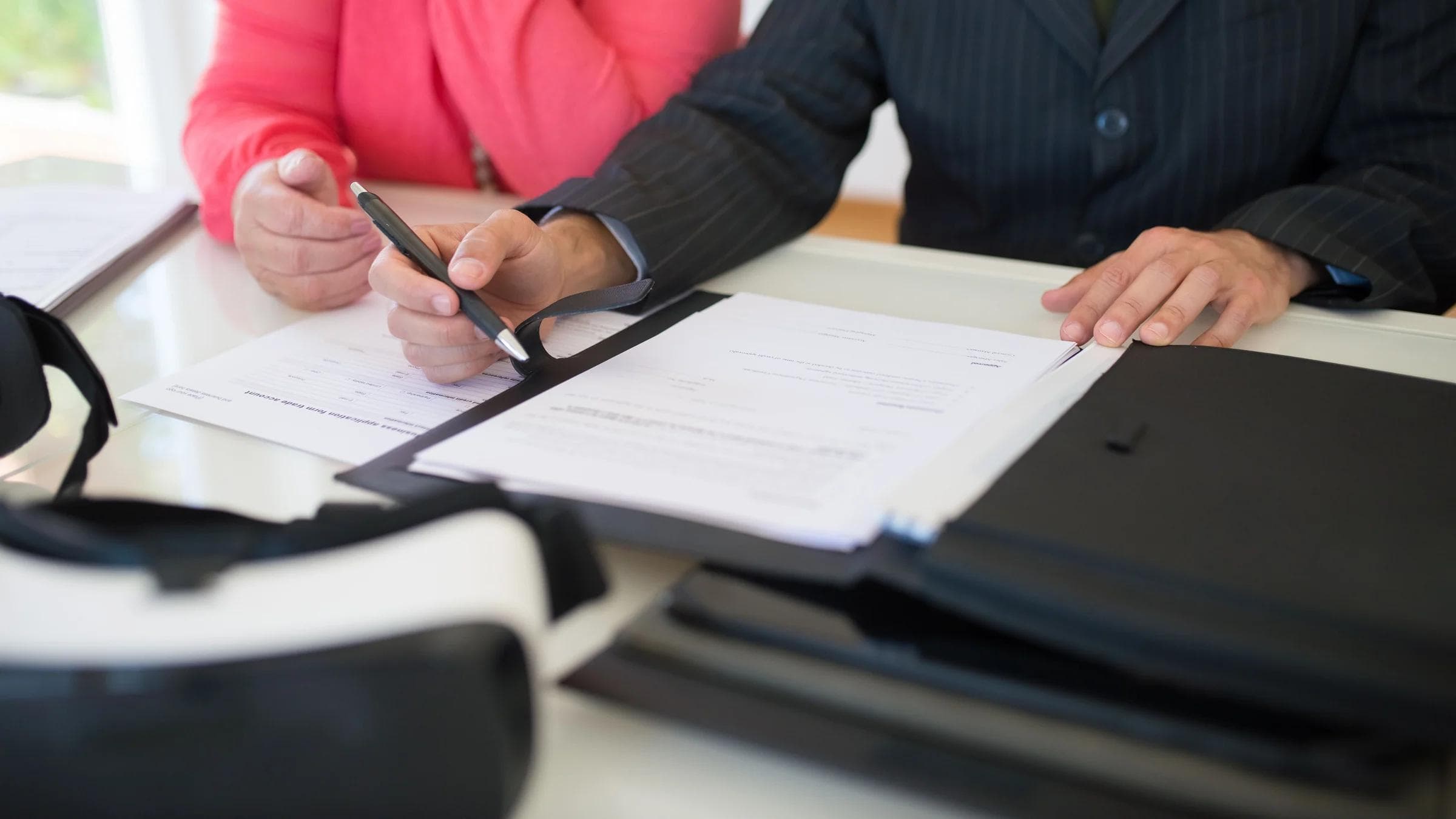 Close-up of professionals signing a business contract indoors, emphasizing agreement and documentation.