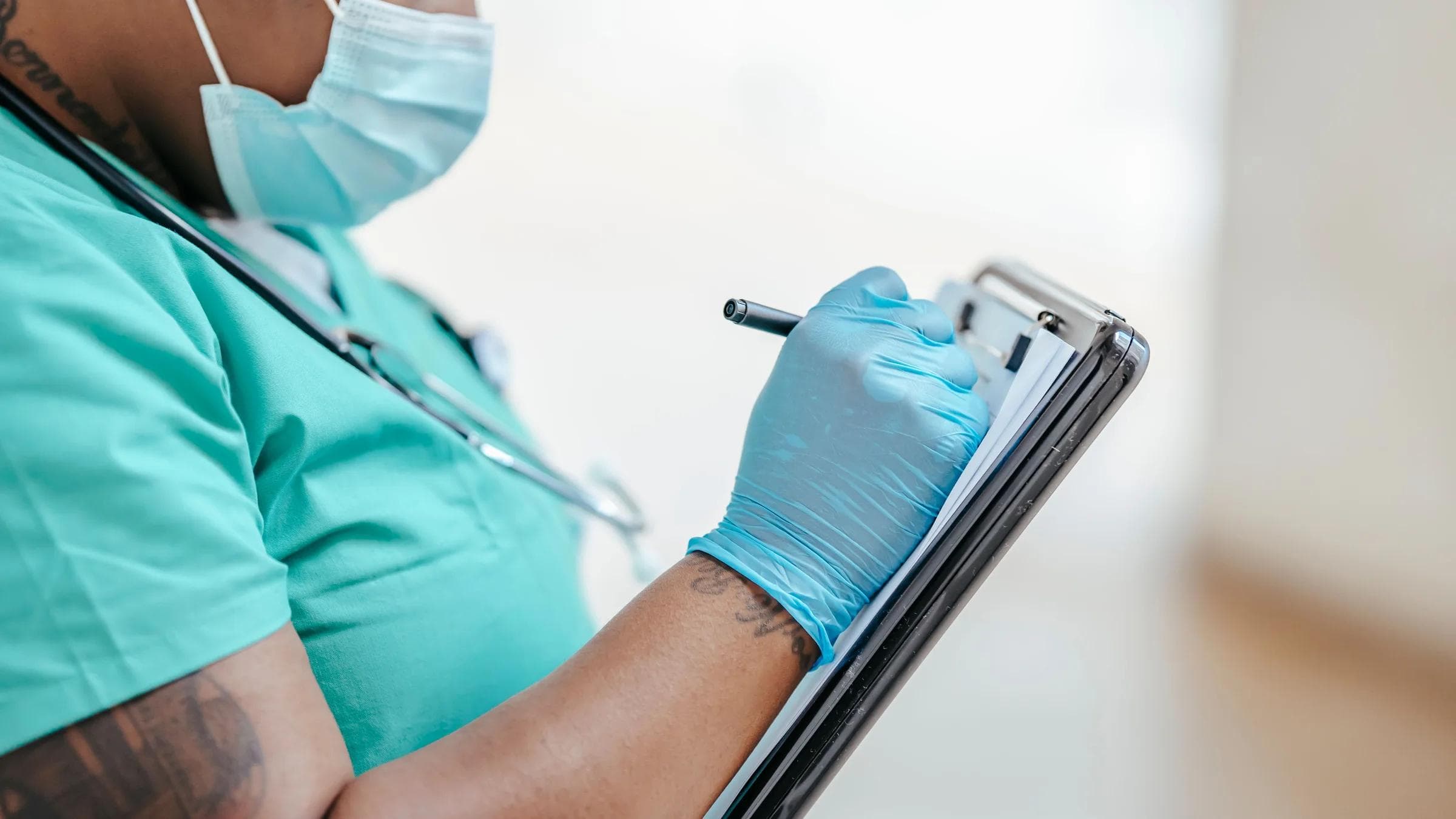 Side view of crop mature black female medic in uniform taking notes on paper document on clipboard.