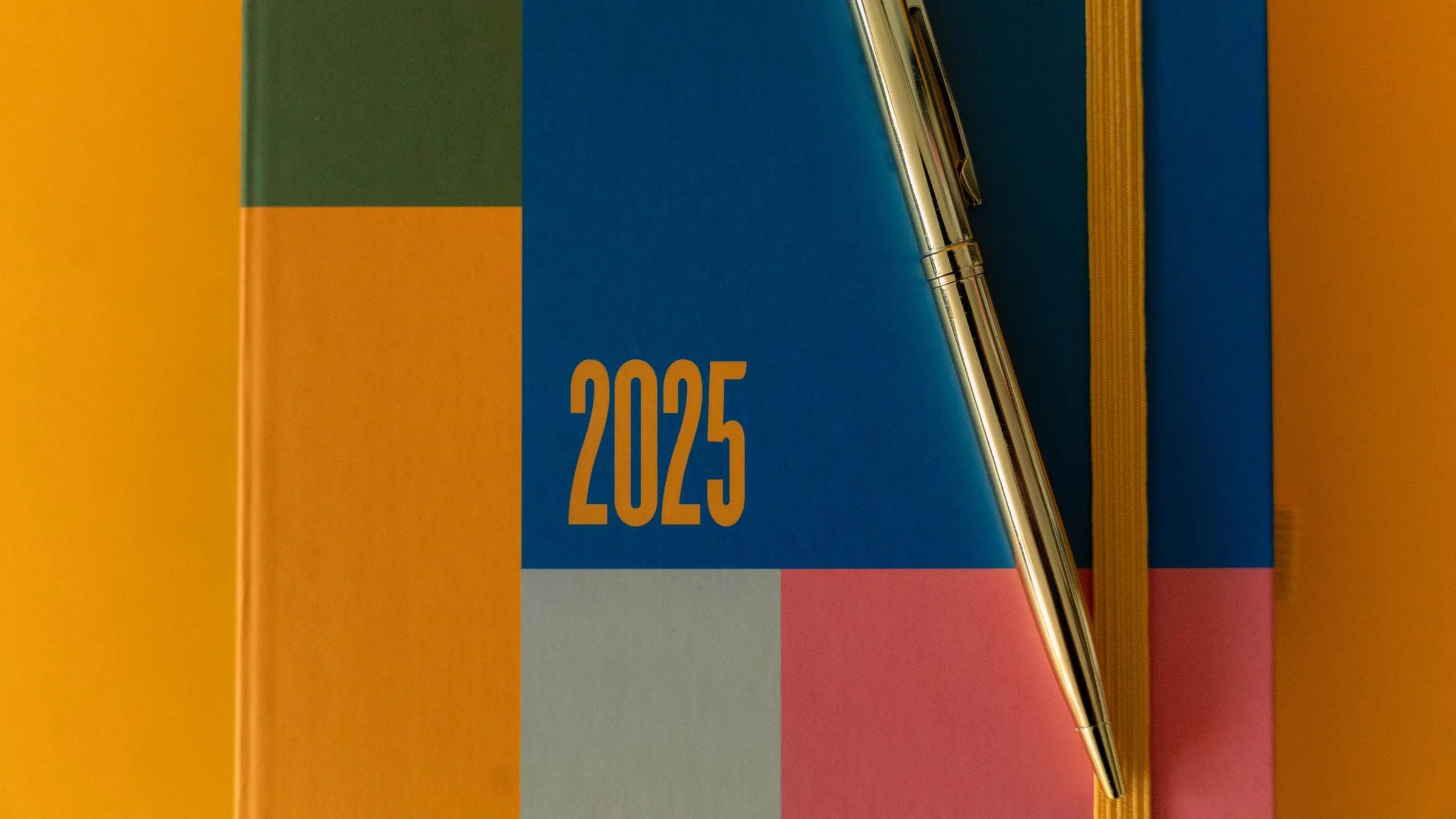 A vibrant 2025 planner with a pen on a colorful backdrop, ideal for organization.