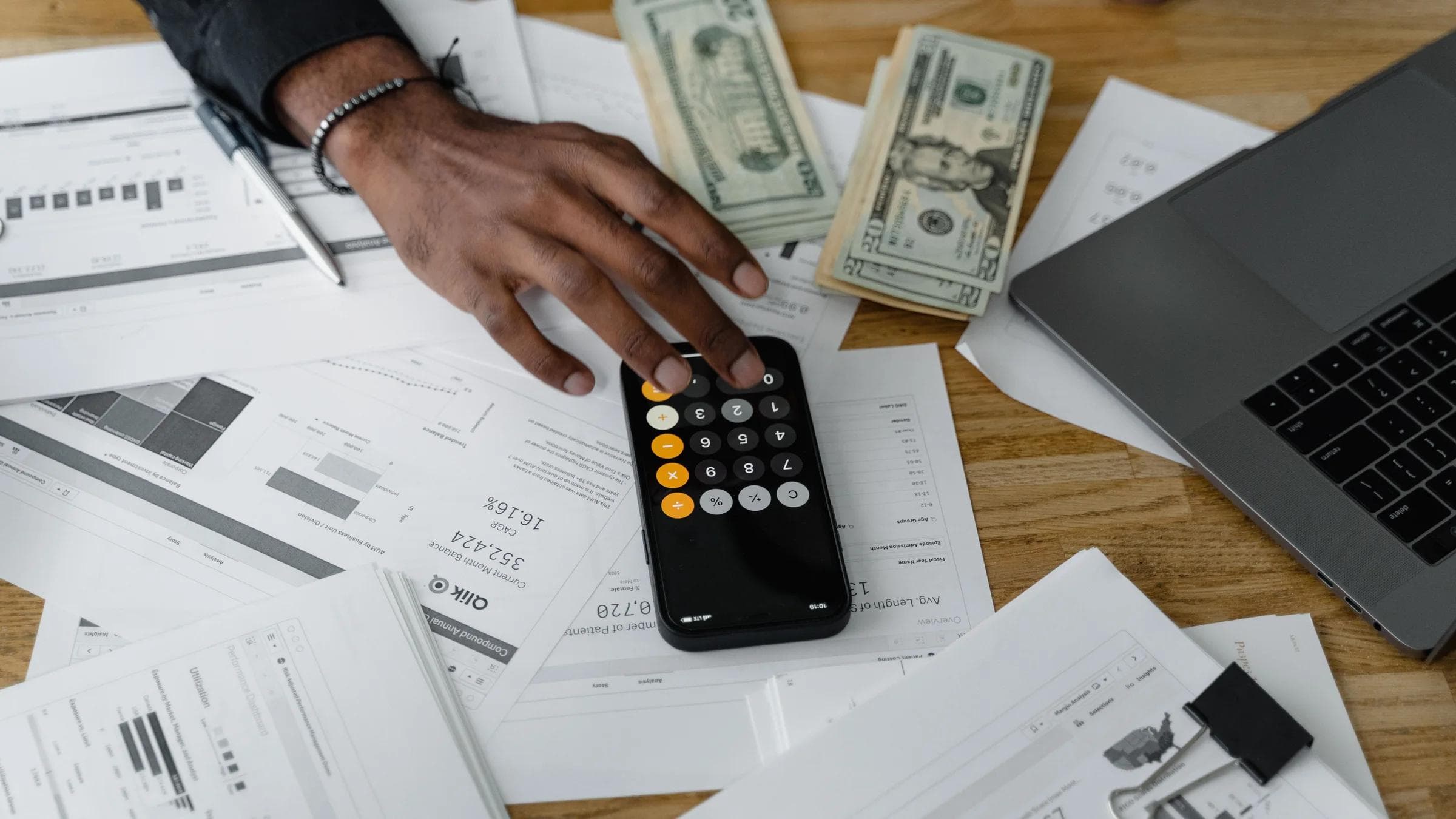 Overhead view of financial documents with calculator, cash, and laptop for financial planning.