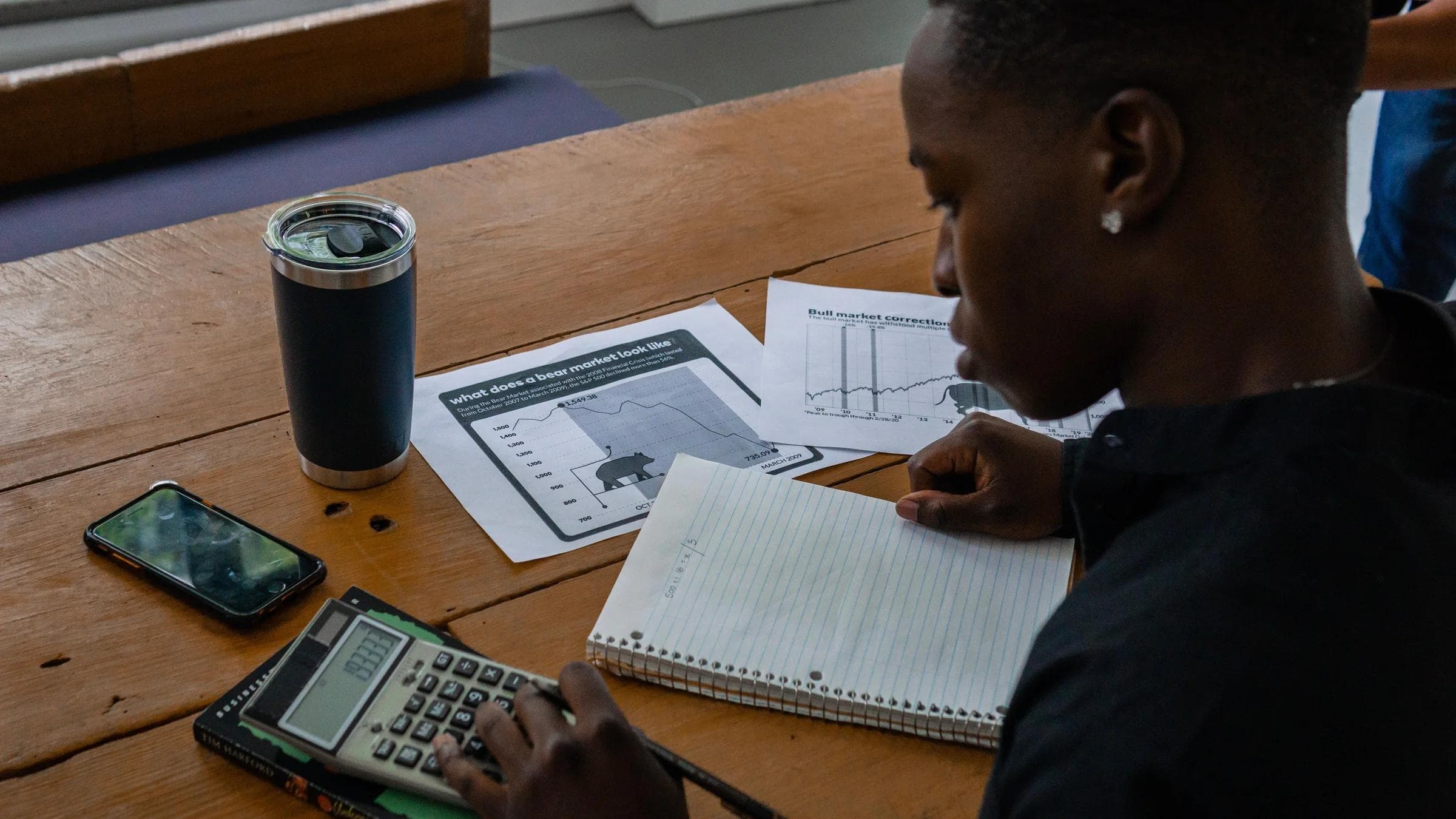 Young professional evaluating financial data using a calculator and notes.