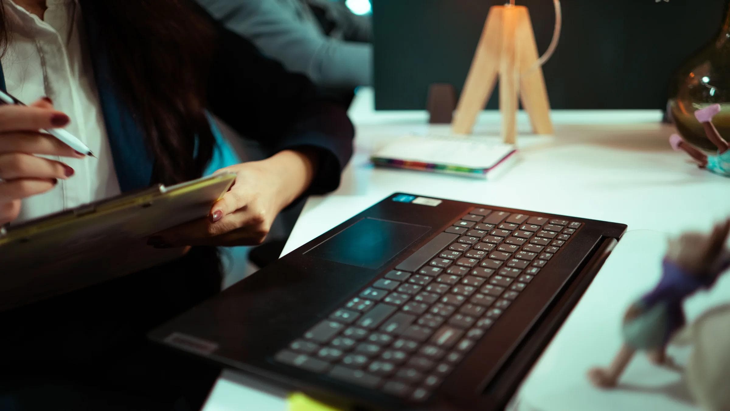 Businesswoman taking notes while working on a laptop in an office.