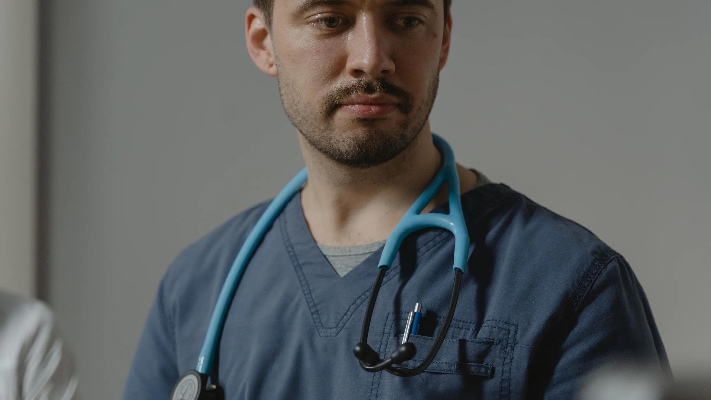 Close-up of a male healthcare worker with stethoscope in a clinical setting.