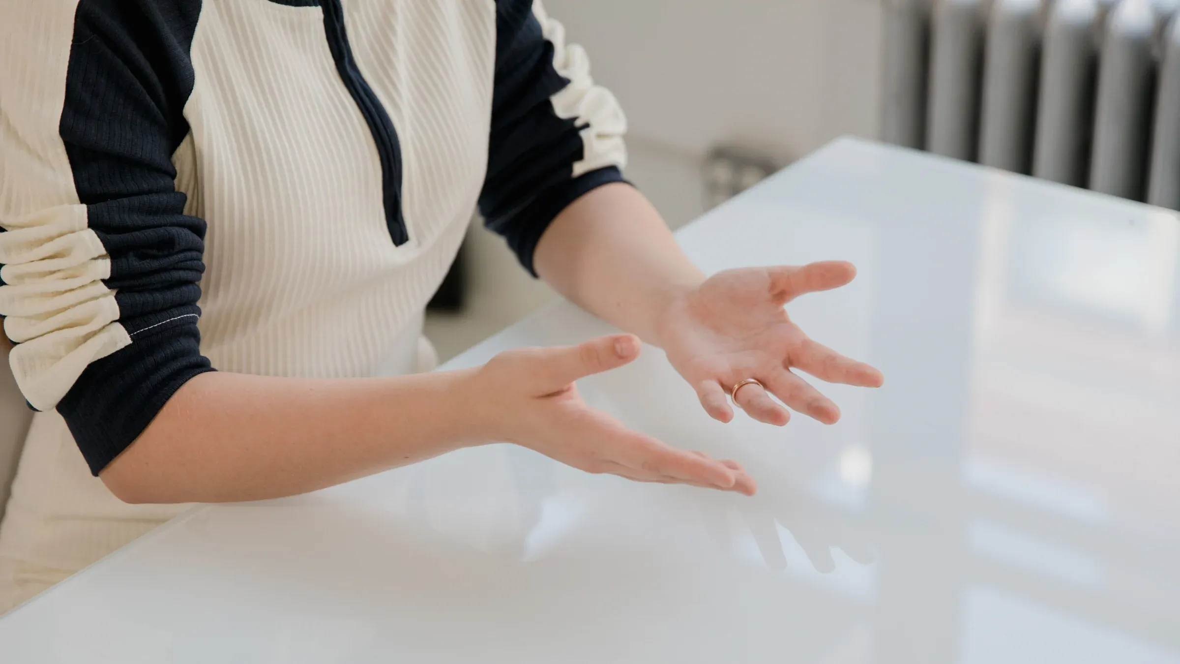 Close-up of a person's hands gesturing expressively indoors.