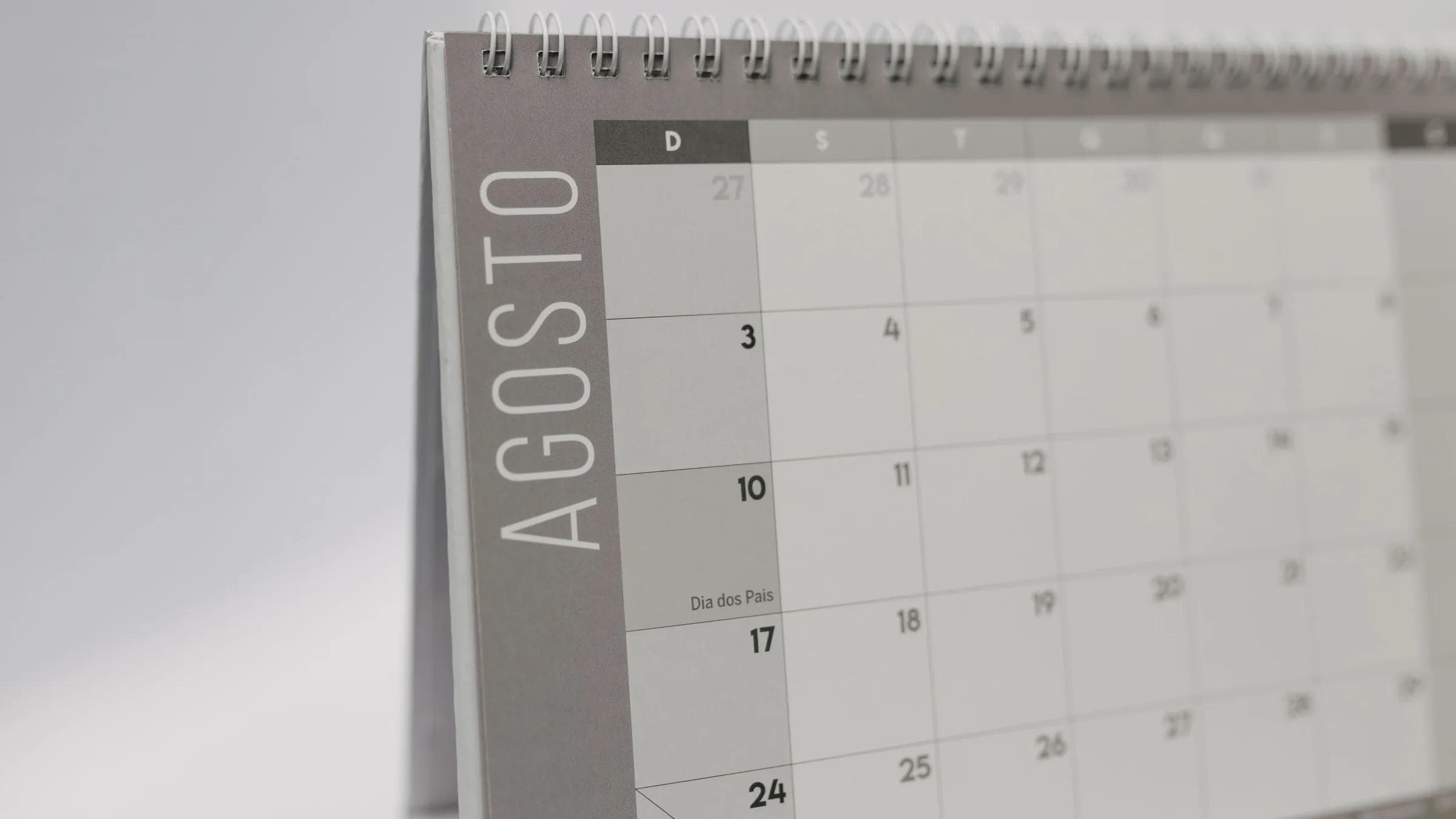 Close-up of a desk calendar showing August in Portuguese with a minimalist layout.