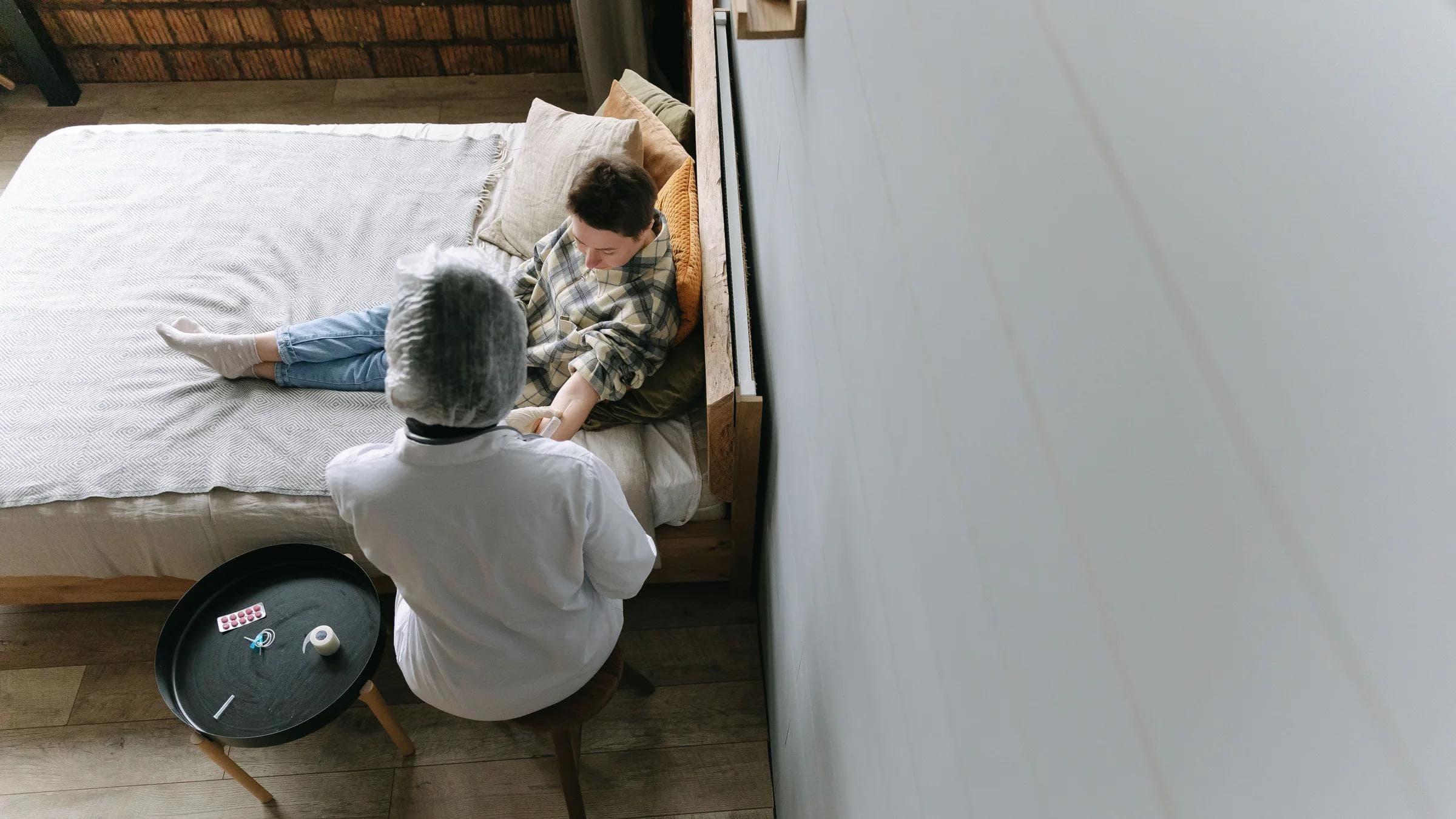 A doctor tends to a young patient in a cozy bedroom environment.