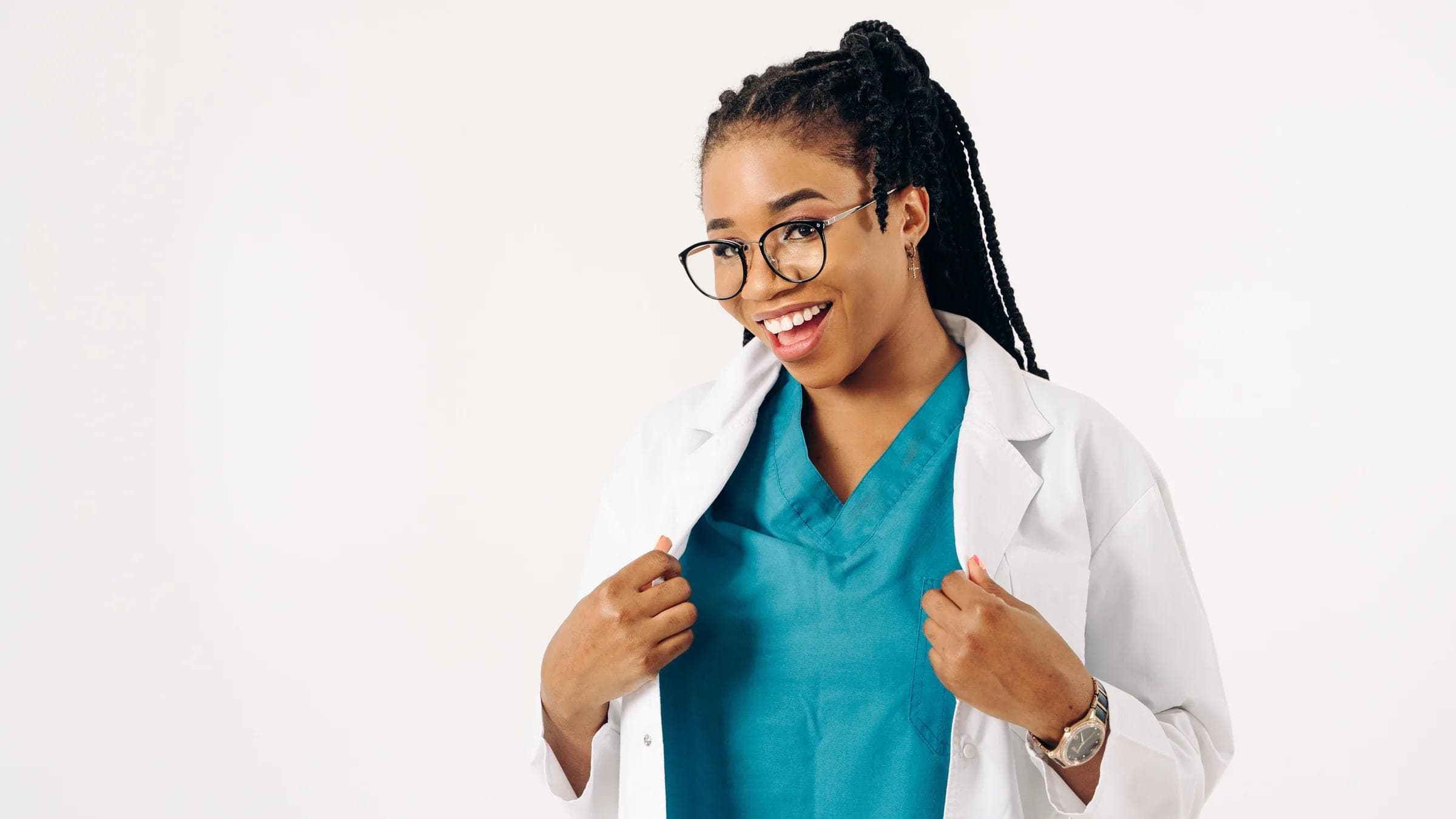 Confident female doctor smiling in a white coat with teal scrubs, embodying professionalism and approachability.
