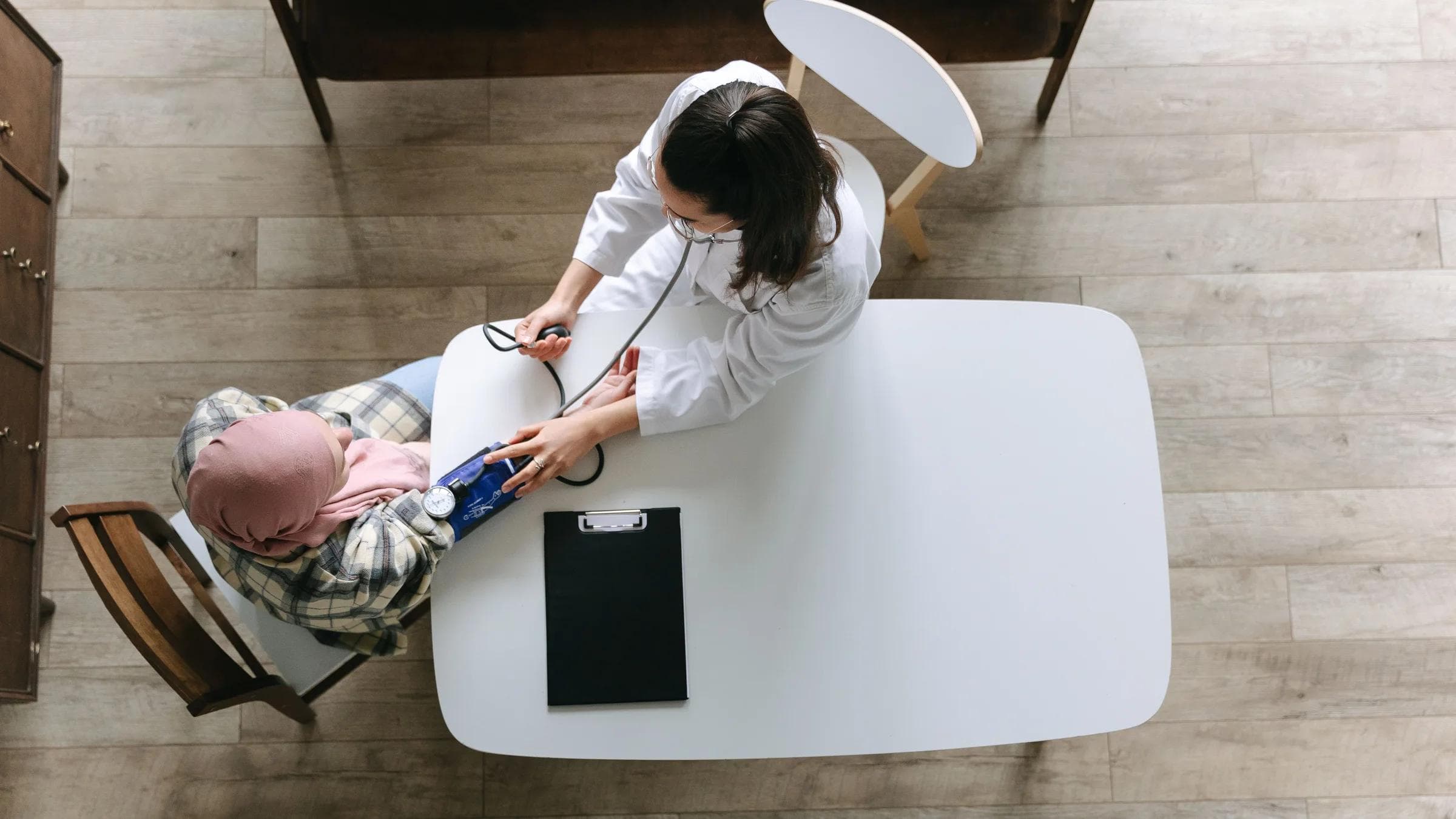 Overhead view of a doctor checking a patient's blood pressure during a healthcare consultation indoors.