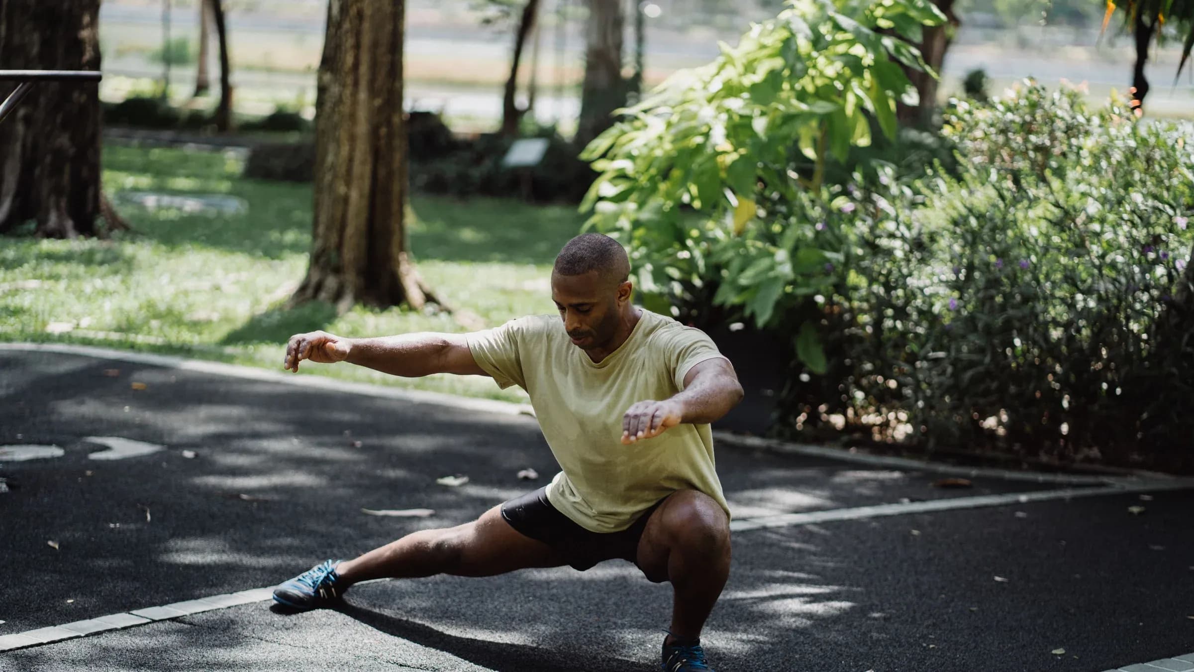 Fit man doing stretching exercise in a park, promoting wellness and healthy lifestyle.